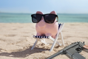 PiggyBank on Beach with gun_shutterstock_266589911